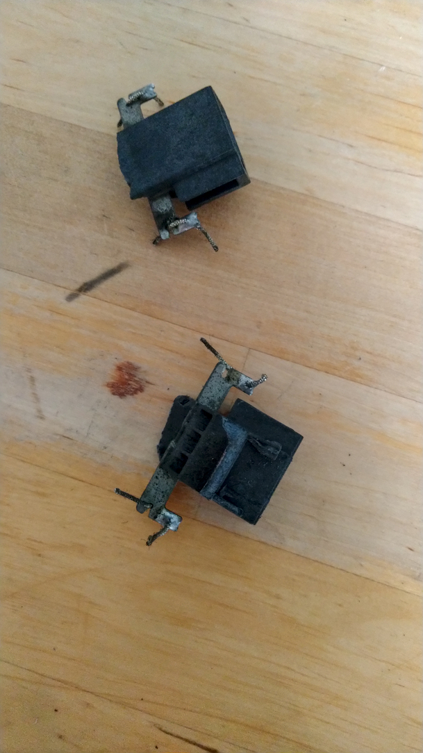 2 prises noires, sale, avec des cables encore soudé sur chacune de leur 2 pattes.