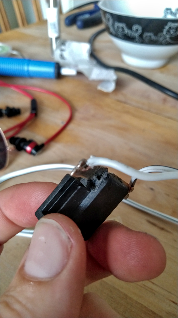 Detail d'une prise noire pour enceinte de voiture où l'on distingue qu'un coin a fondu et est legerement endommagé. La patte métallique proche est donc mal placée