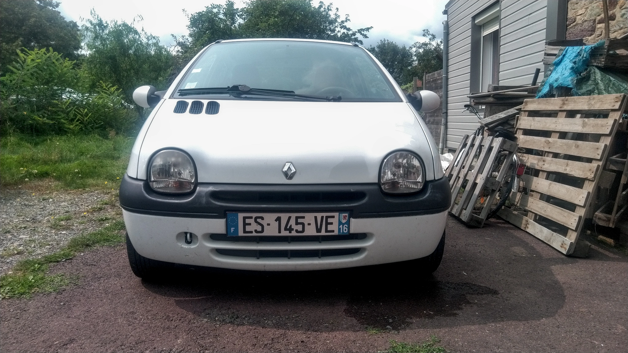 Face avant des Marguerite (Twingo 1 blanche). On distingue bien le phare gauche poli et brillant et celui de droite qui est patiné